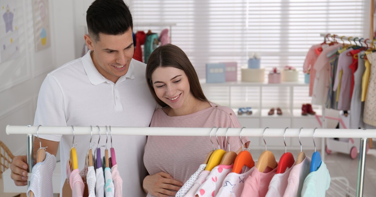 Expectant parents choosing baby clothes in a shop, as China's online maternity and baby prices rose 6.5% in H1 2026