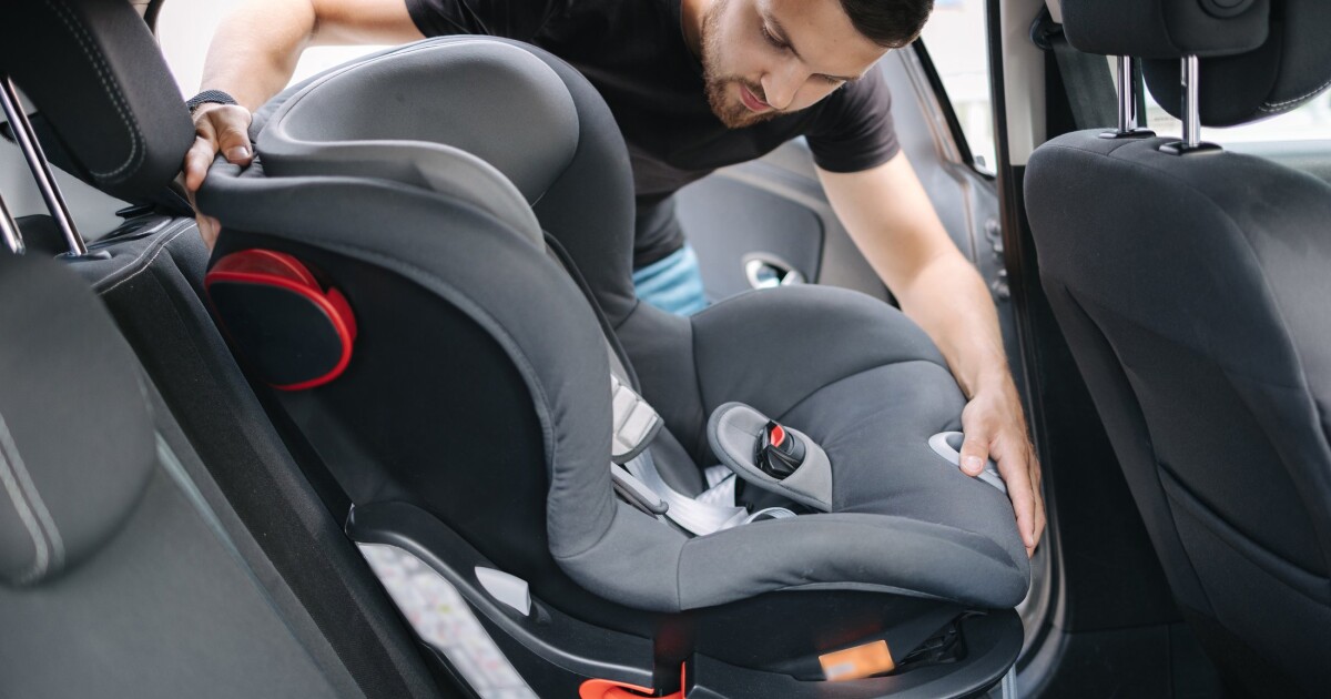 A father fitting a child car seat on the back seat of a car, as China's online car seat sales grew 23.2% in H1 2026