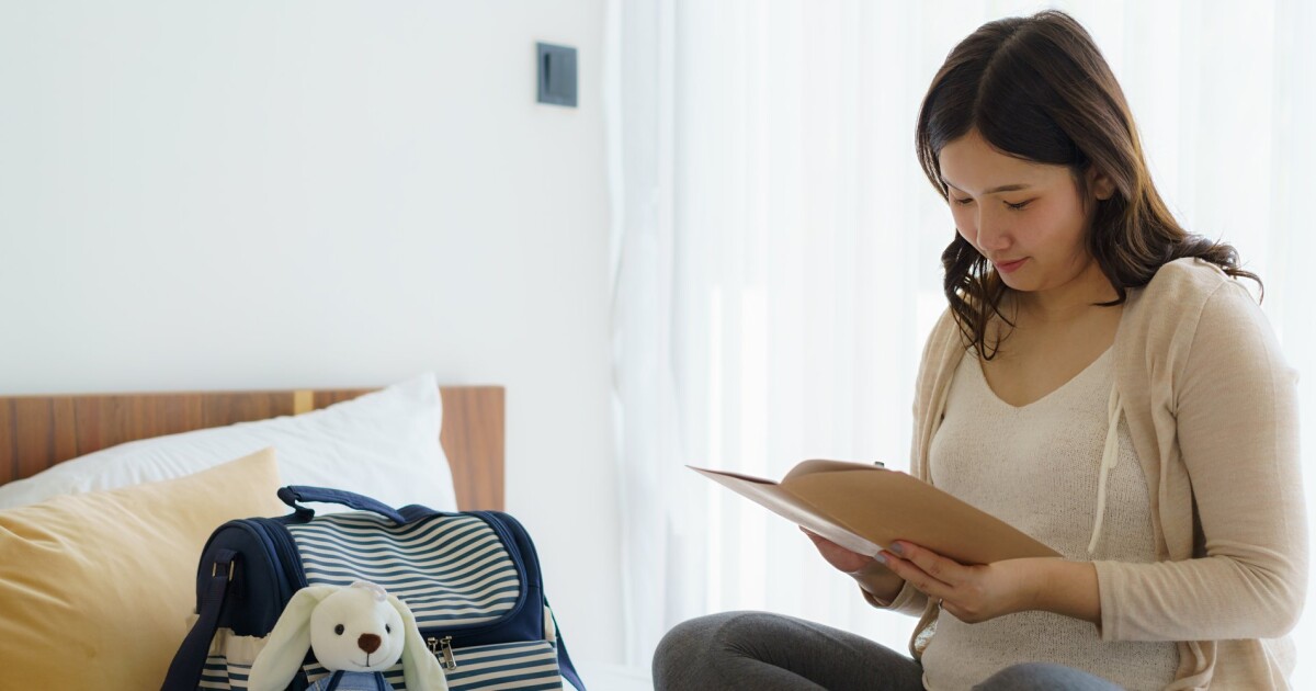 An expectant mother going through a checklist beside a packed bag, as China's online maternity prep sales grew 12.7% in H1 2026