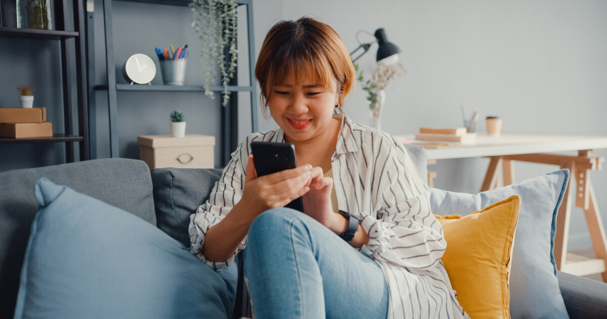 A young woman checking social media on her phone at home